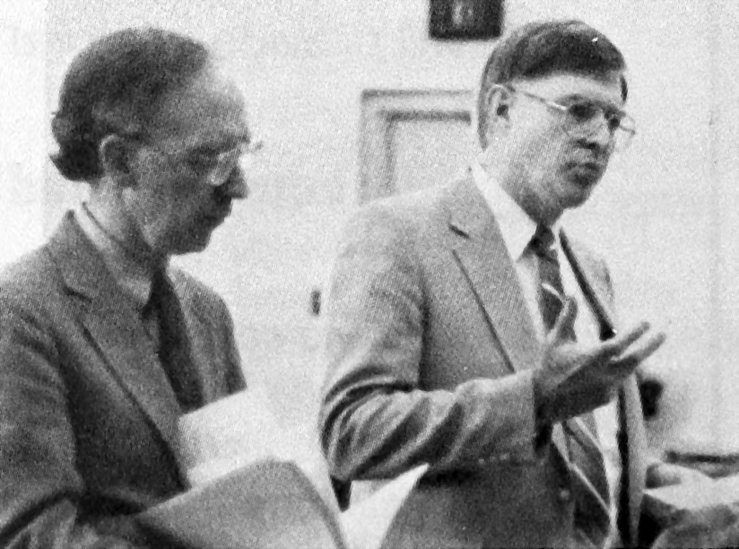 Jim Lapp gesticulates while Ed Metzler stands nearby holding a folder of papers