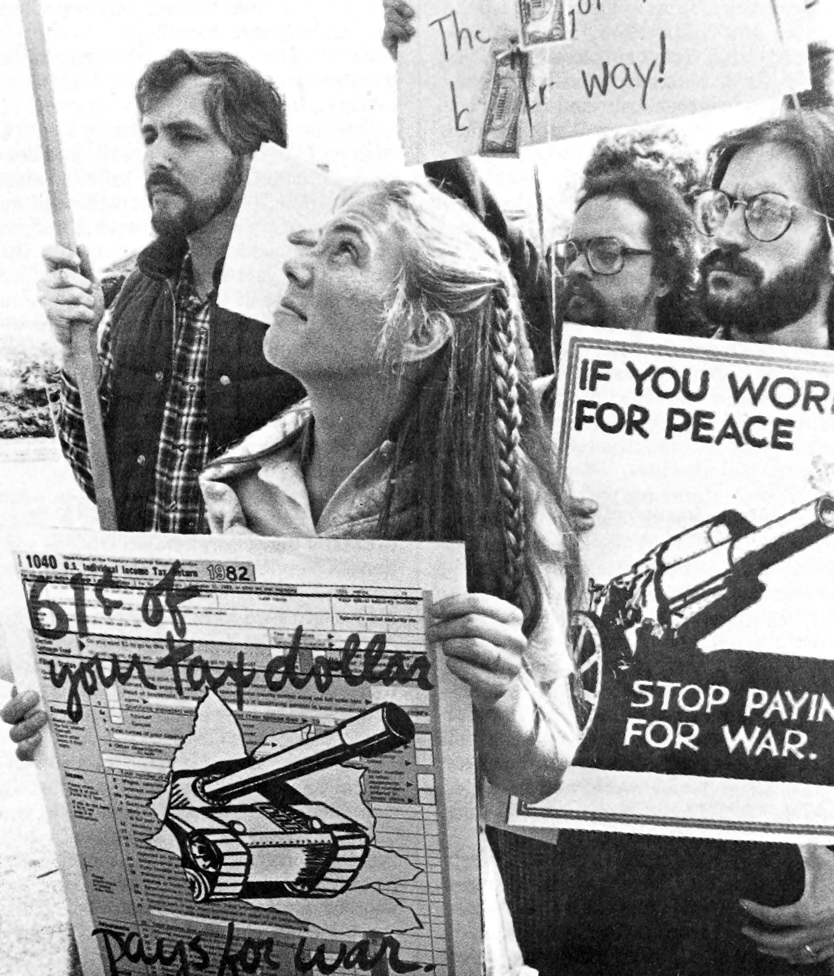 several people carrying signs with slogans like “If you work for peace, stop paying for war” and “61¢ of your tax dollar pays for war”