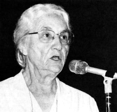 A head and shoulders photo of Ruth Brunk Stoltzfus speaking before a microphone.